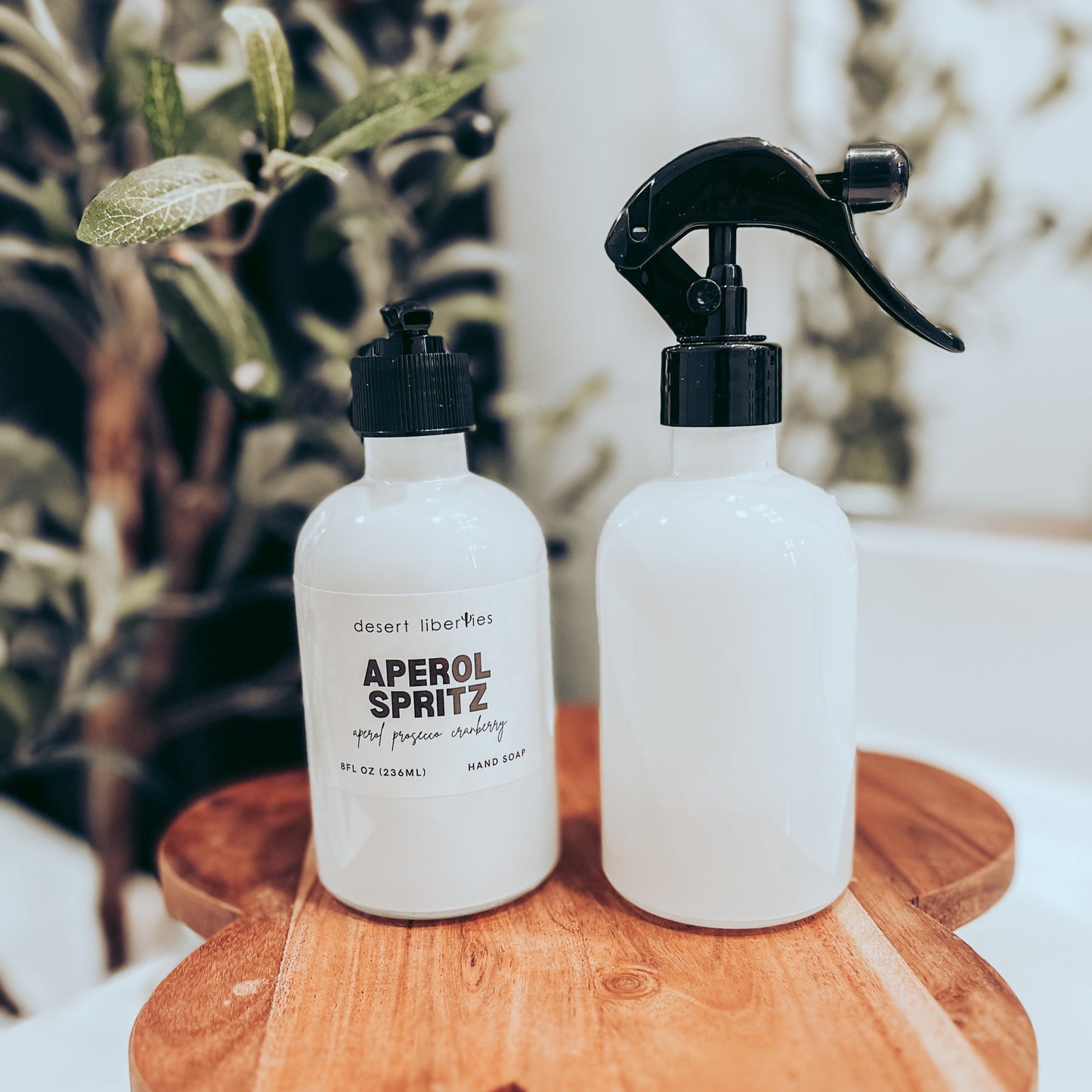 Soap bottle next to an unlabeled spray bottle on a wood surface and olive tree in the background. 