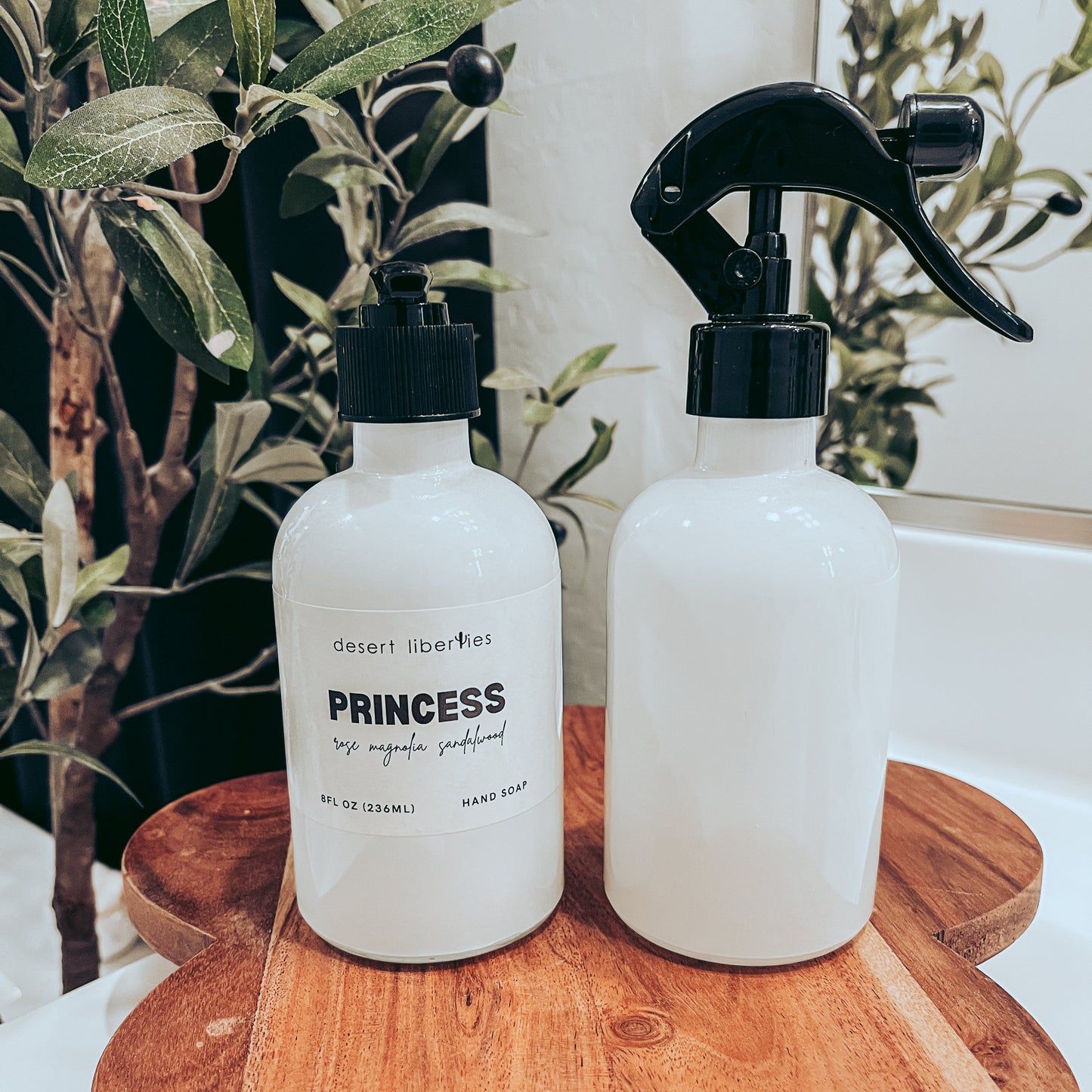 Soap bottle next to an unlabeled spray bottle on a wood surface and olive tree in the background. 