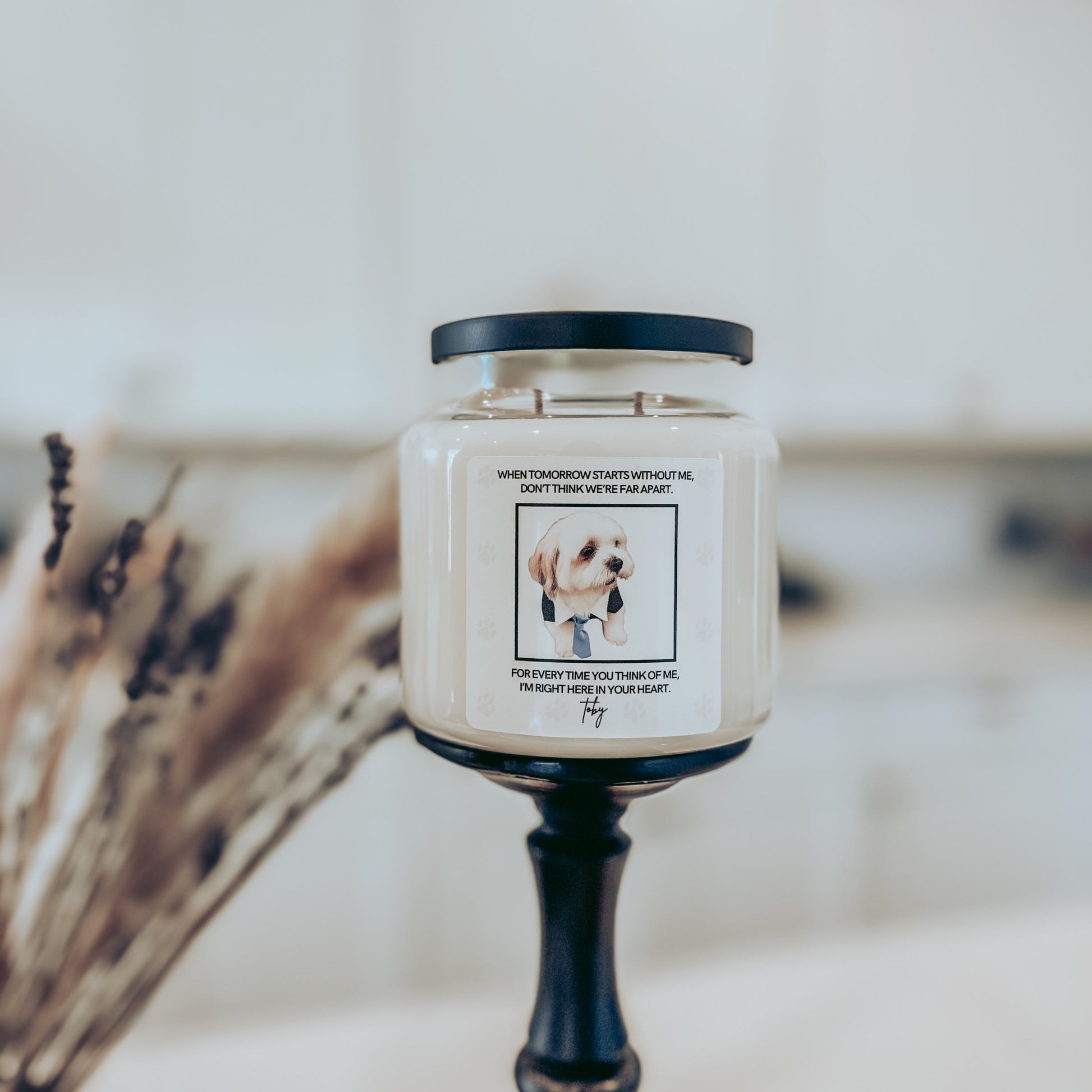 Candle with a label featuring a dog illustration on a decorative stand.