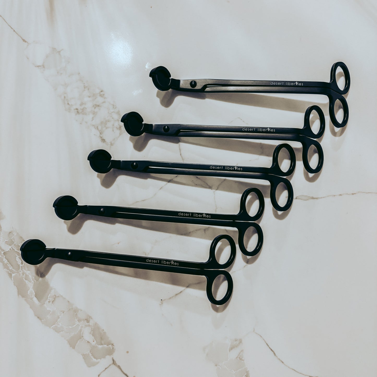 Set of black wick trimmers on a marble surface
