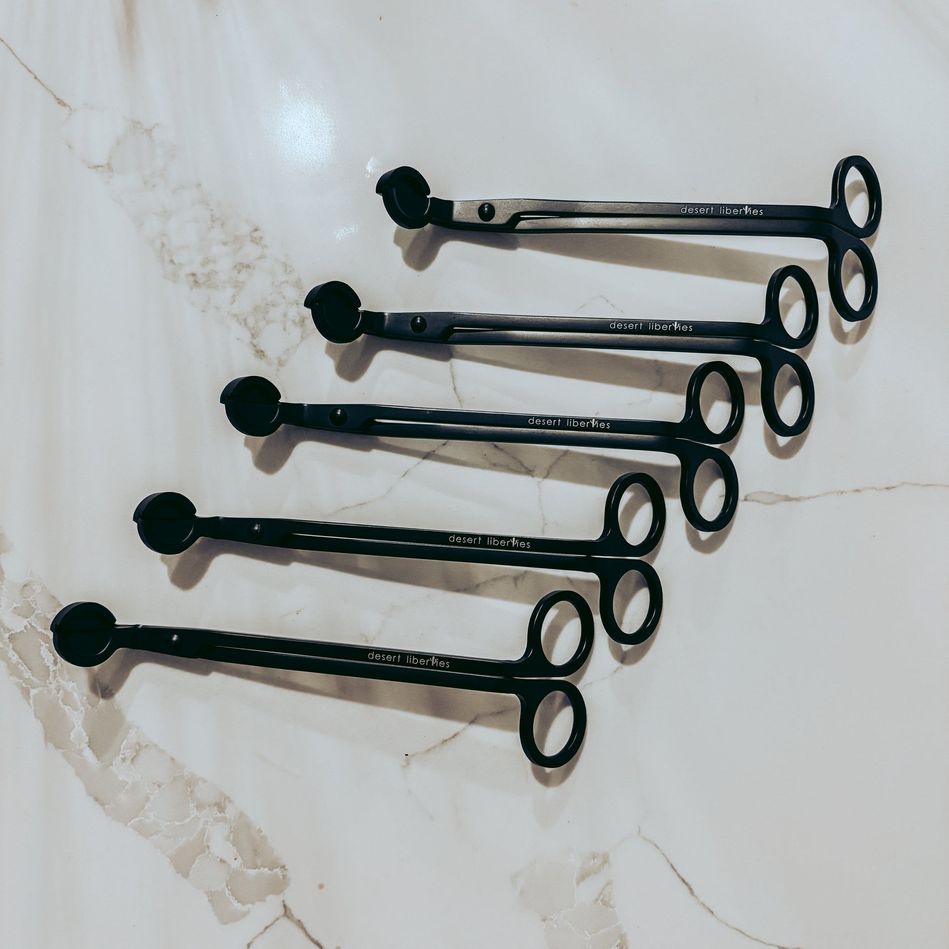 Set of black wick trimmers on a marble surface