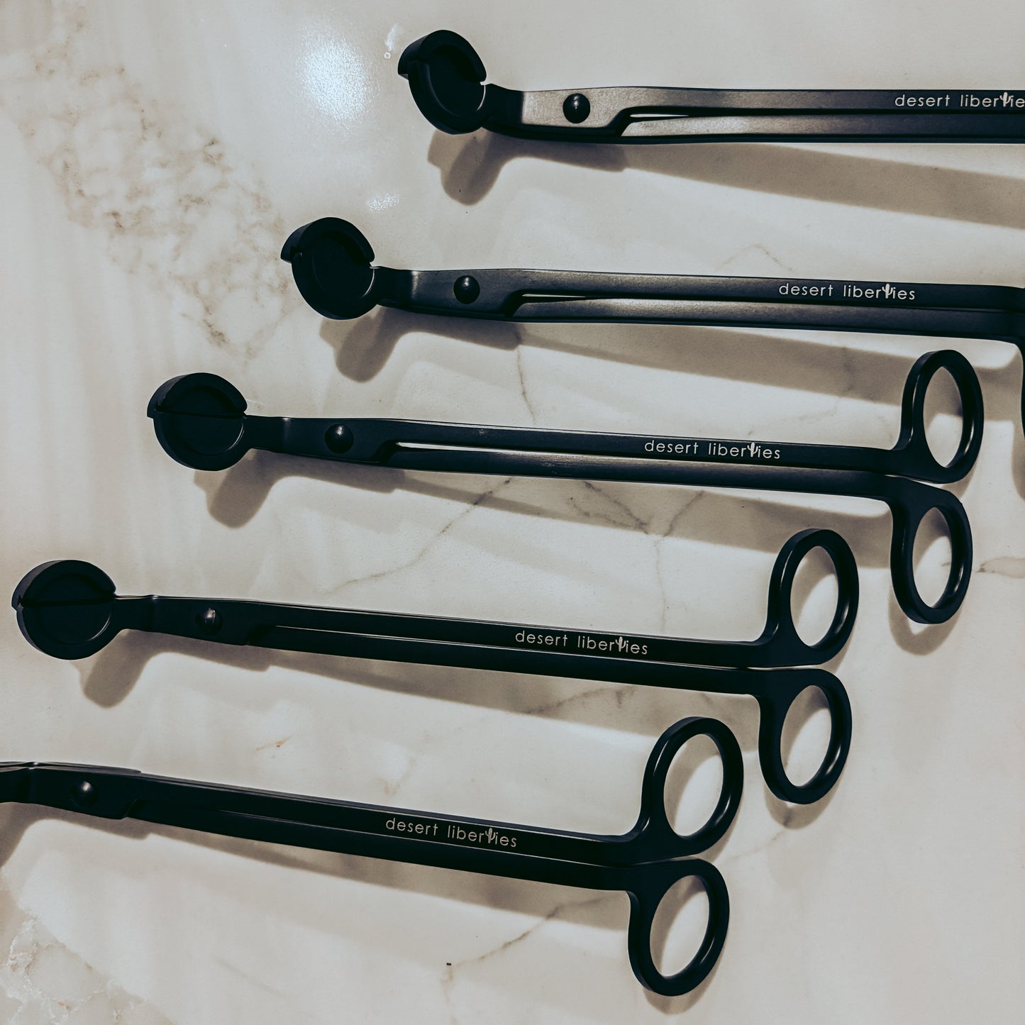 Set of black wick trimmers on a marble surface