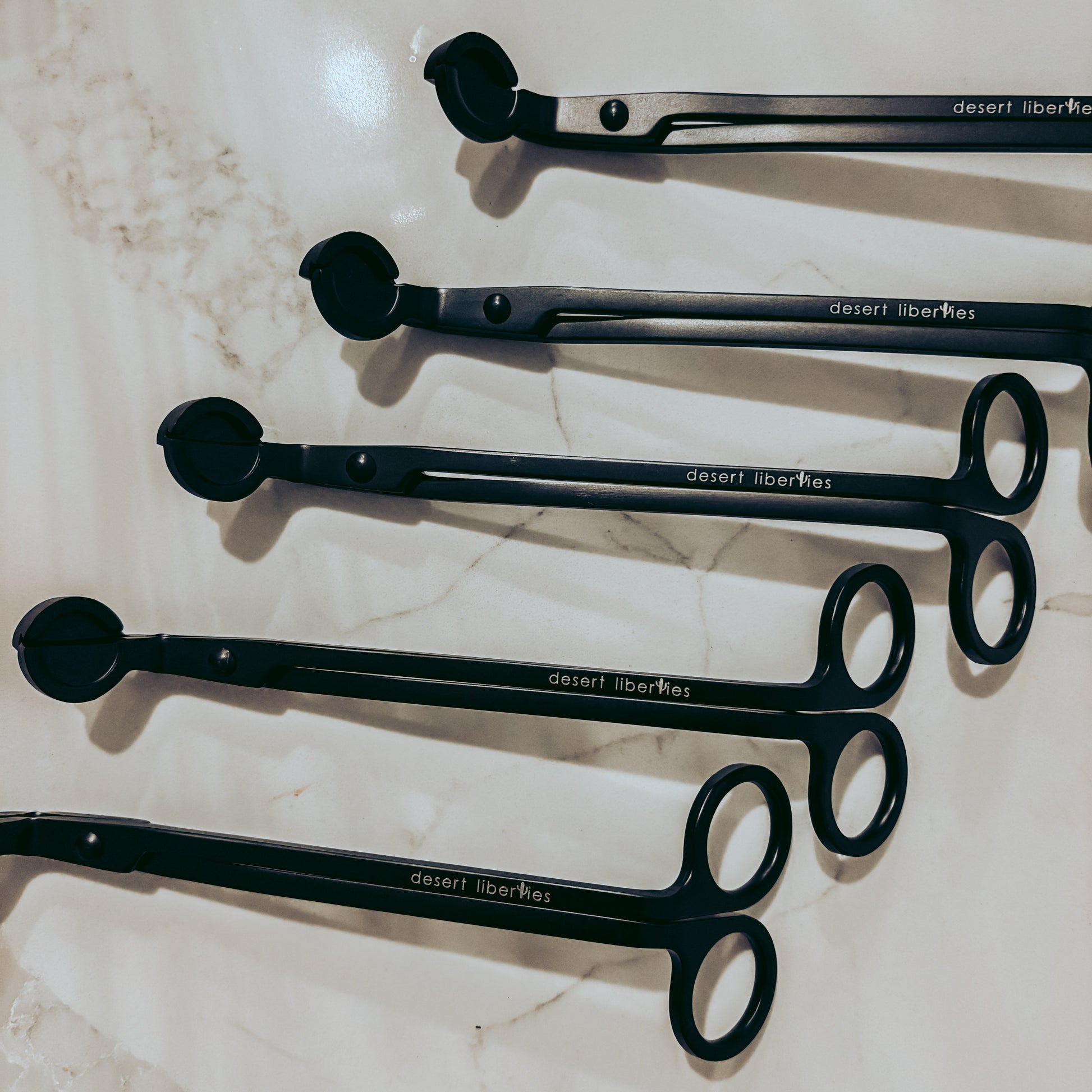 Set of black wick trimmers on a marble surface