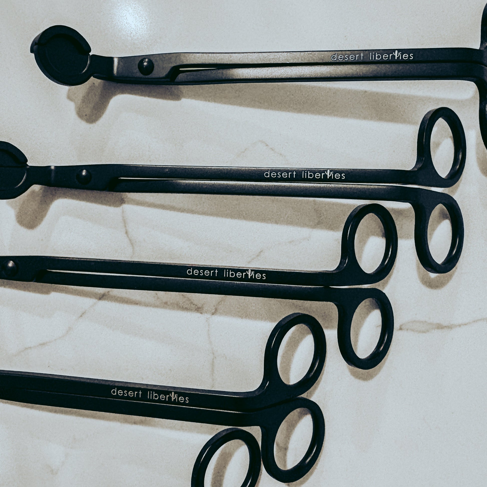 Set of black wick trimmers on a marble surface