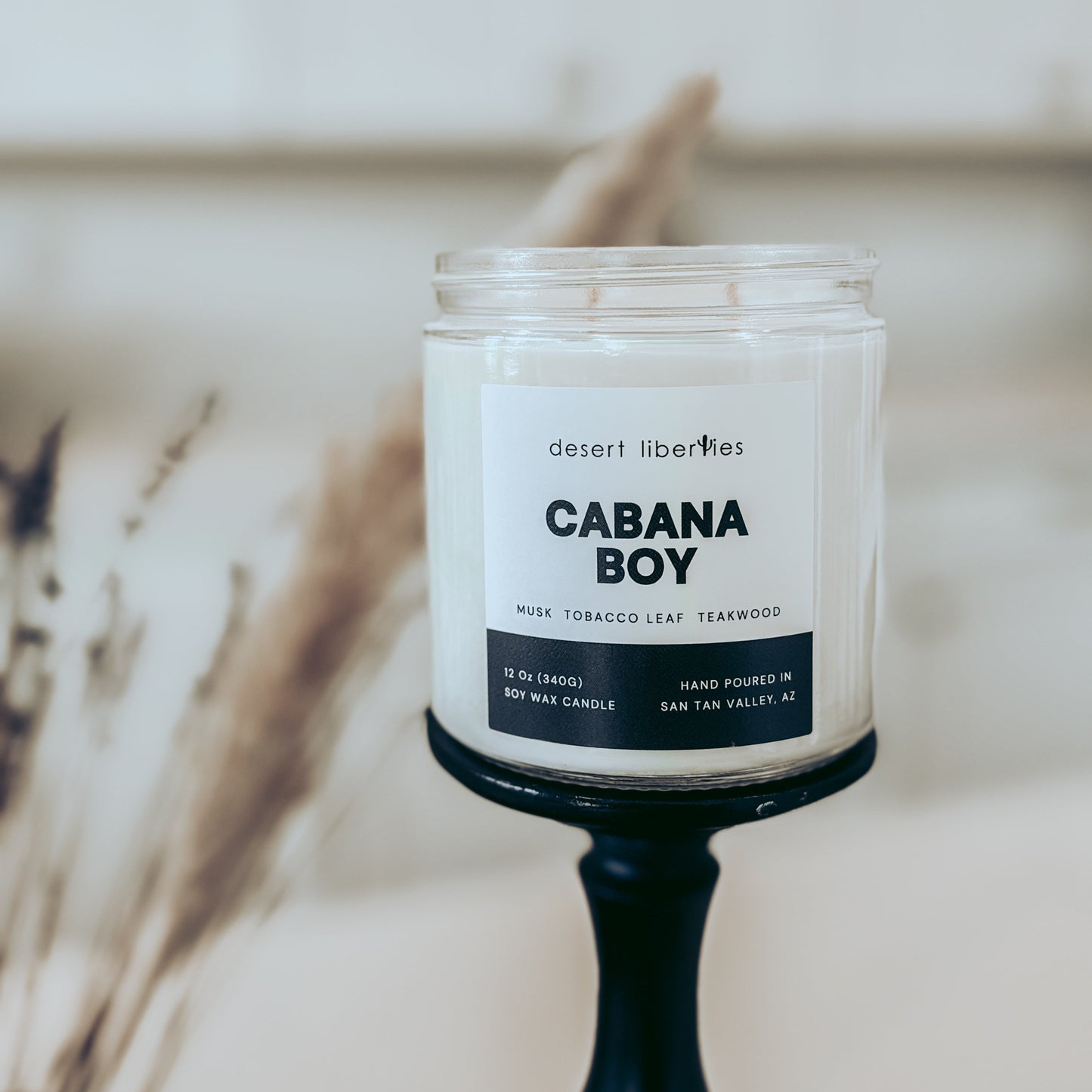 Candle labeled 'Cabana Boy' by Desert Liberties on a stand with a blurred background