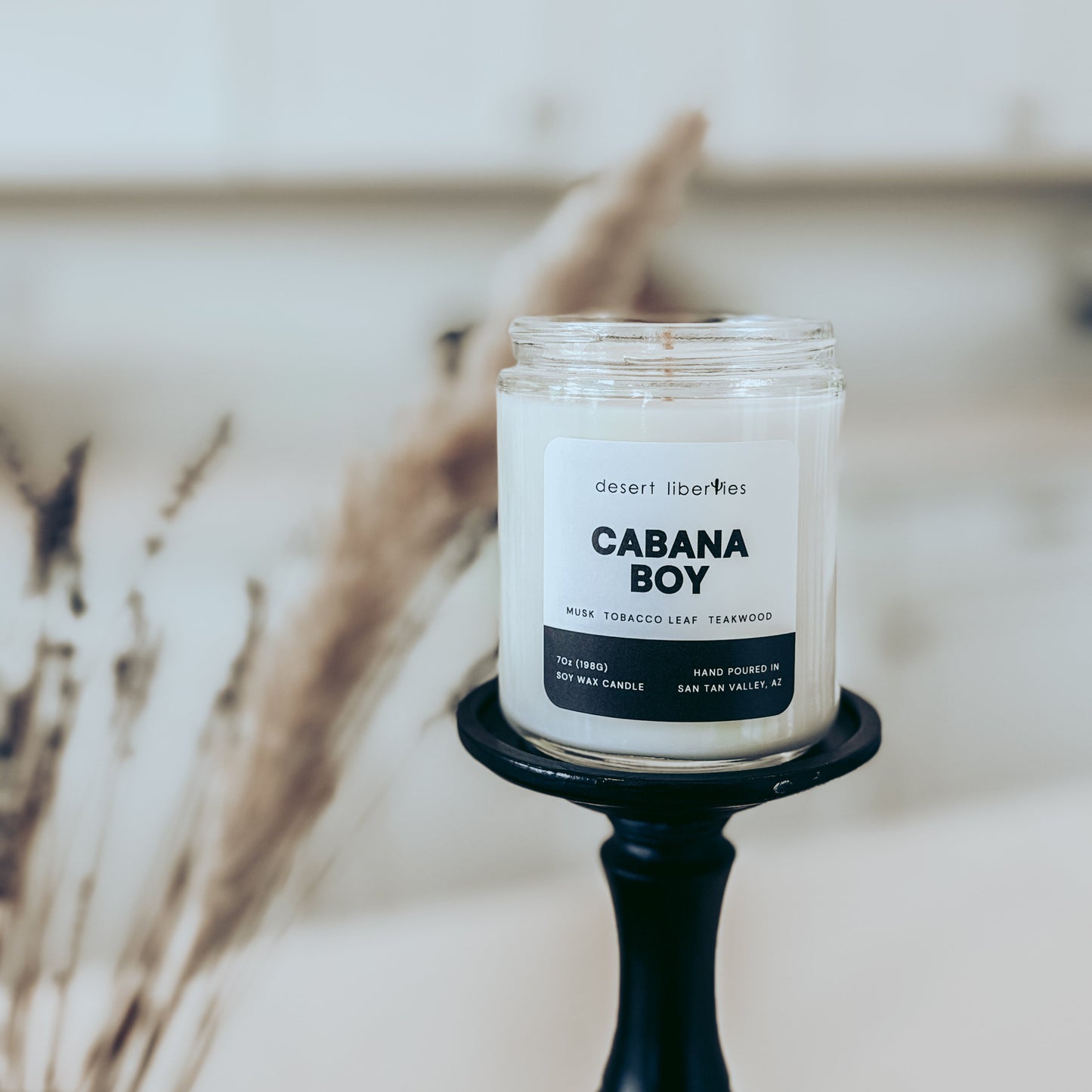 Candle labeled 'Cabana Boy' on a black holder with a blurred background