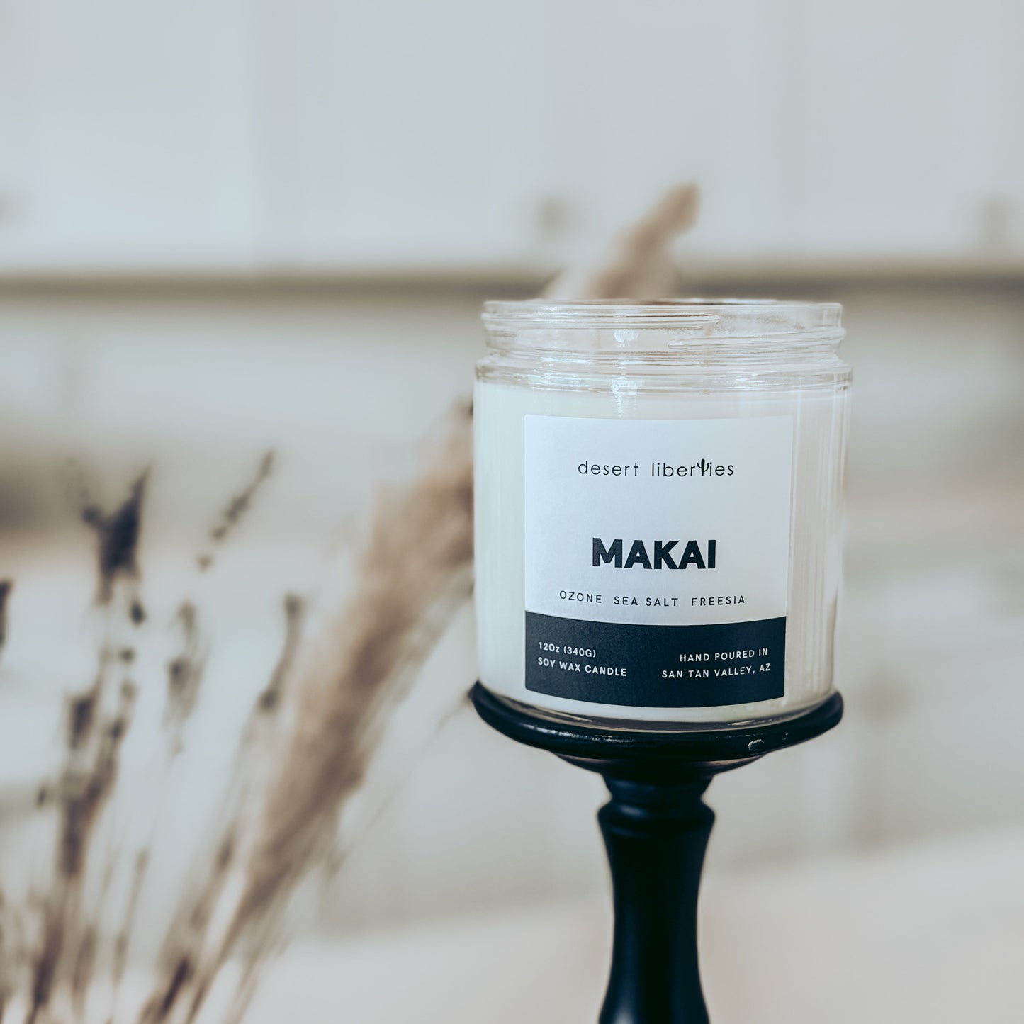 Candle with 'MAKAI' label on a black holder against a neutral background