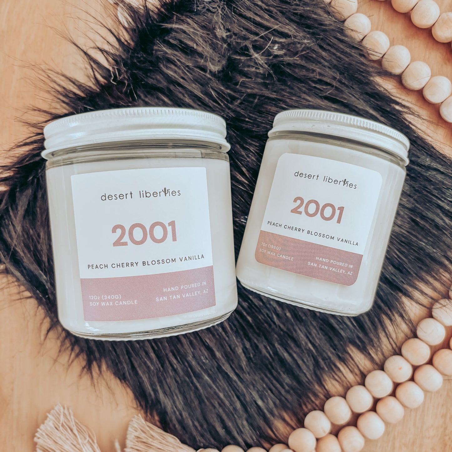 Two candles labeled '2001' on a wooden surface with decorative beads.