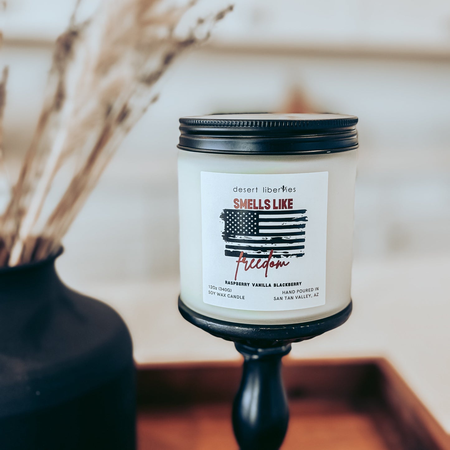 Candle in a black holder with a label on a wooden surface