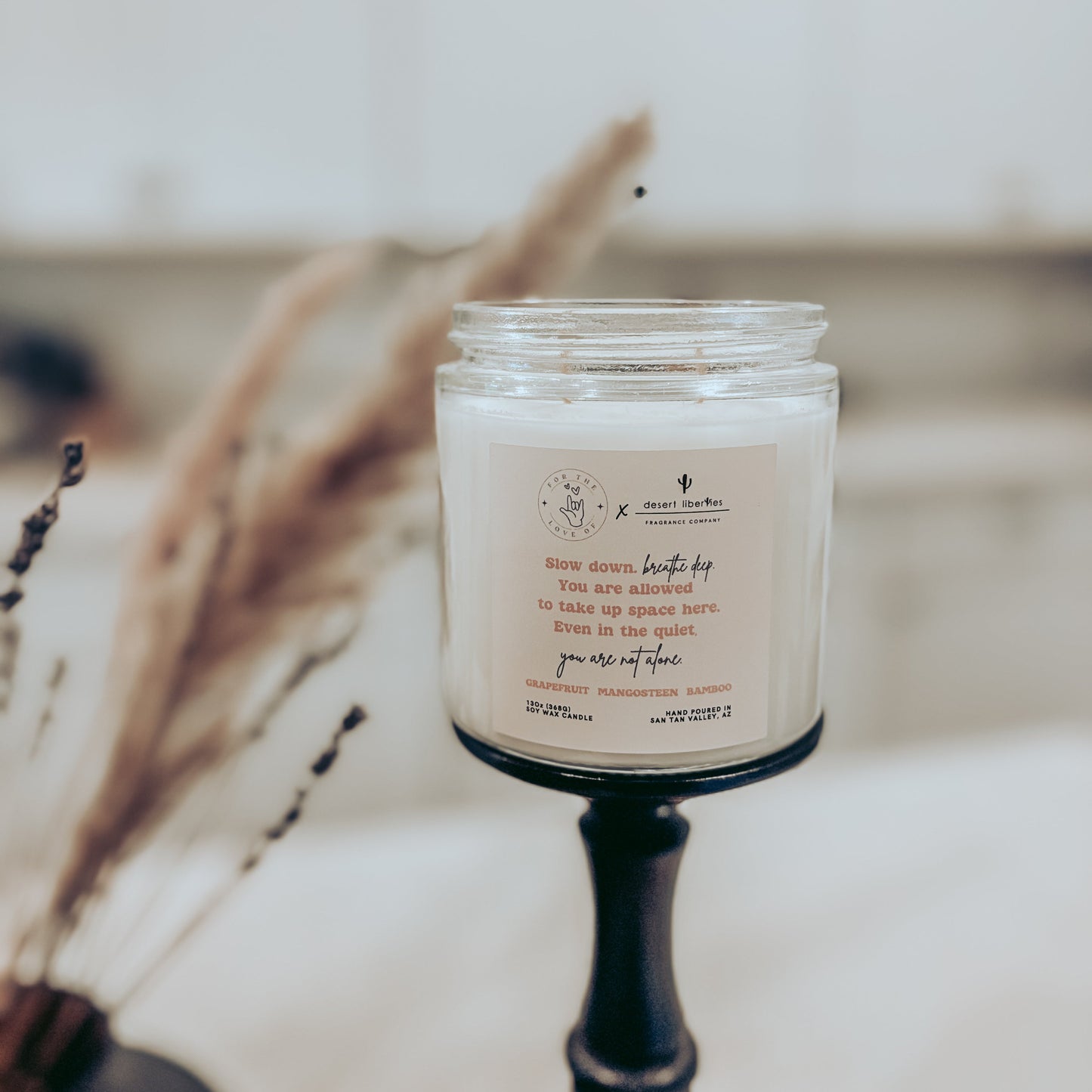 Candle in a glass jar with a label on a wooden surface, blurred background