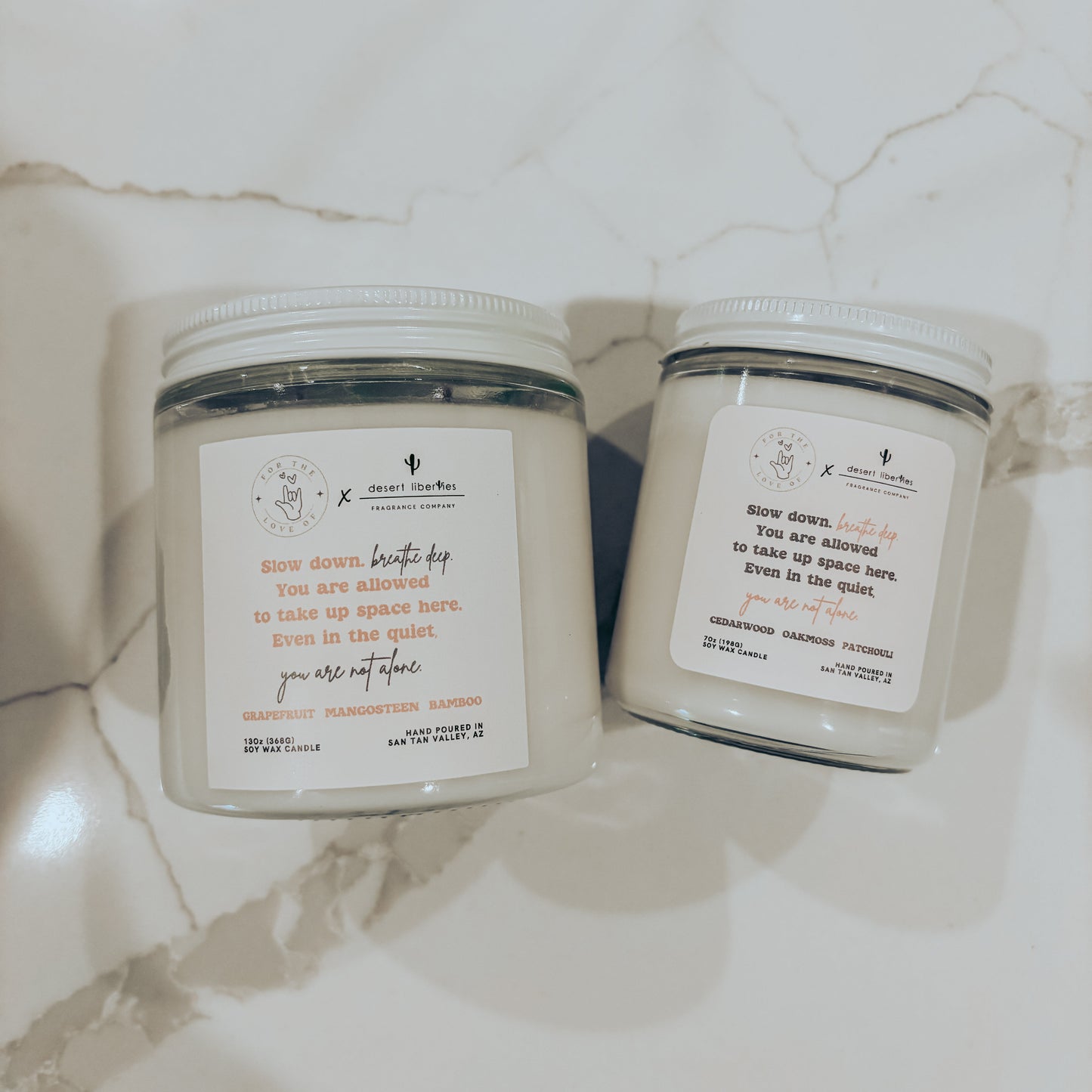 Two candles with labels on a marble surface