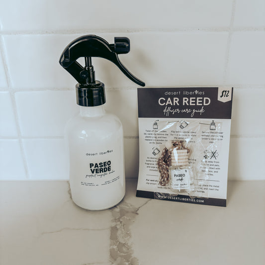 Spray bottle labeled 'Paseo Verde' next to a car care guide on a tiled surface.