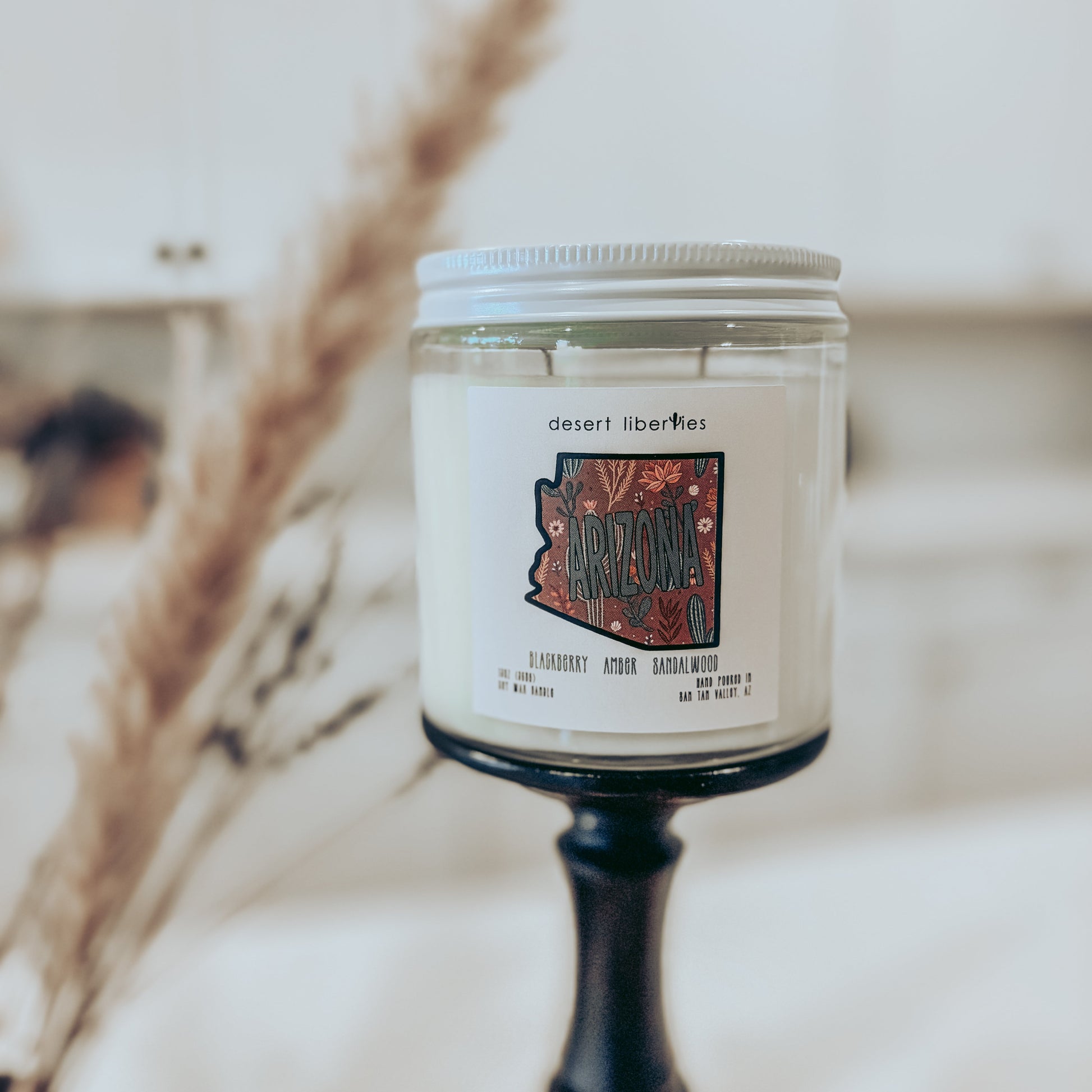 Candle with a label on a stand against a blurred background